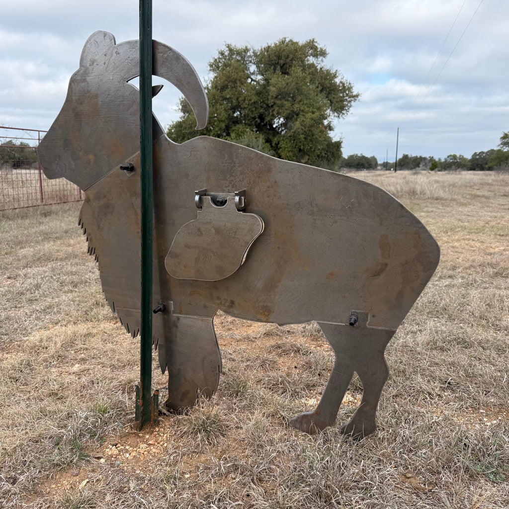 AR500 Steel Aoudad ram target on a t-post stand in an open field with trees in the background