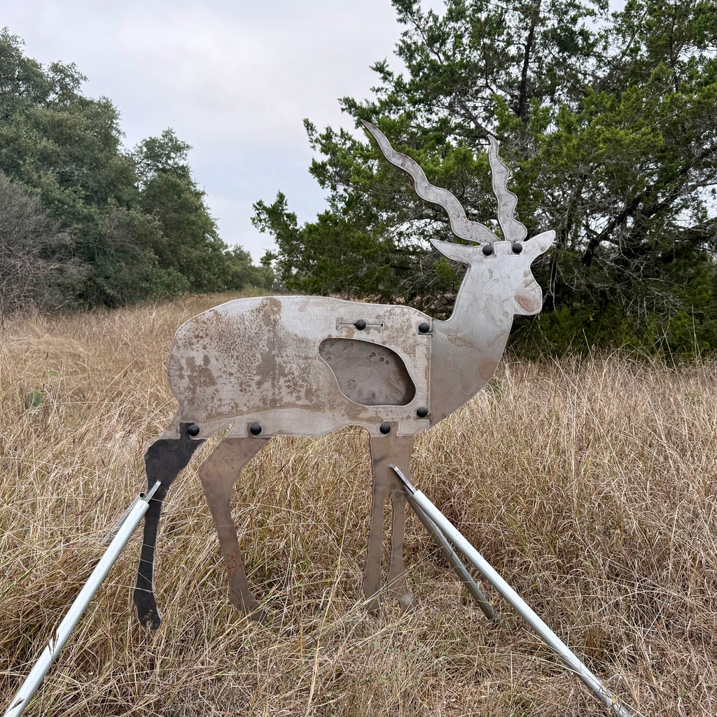 AR500 Steel Blackbuck target on a stand in a grassy outdoor area with trees in the background