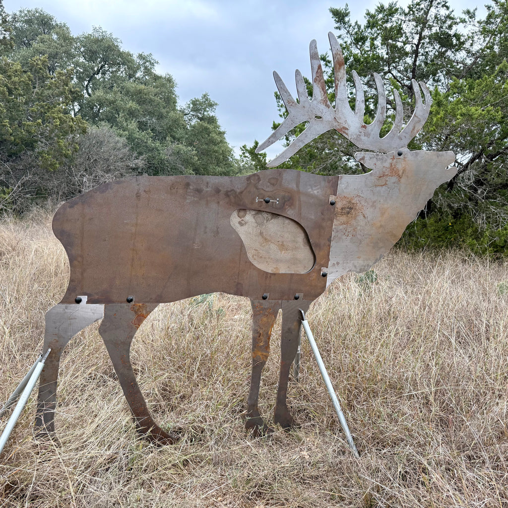AR500 Steel Elk Bull target on a stand in a grassy outdoor area with trees in the background