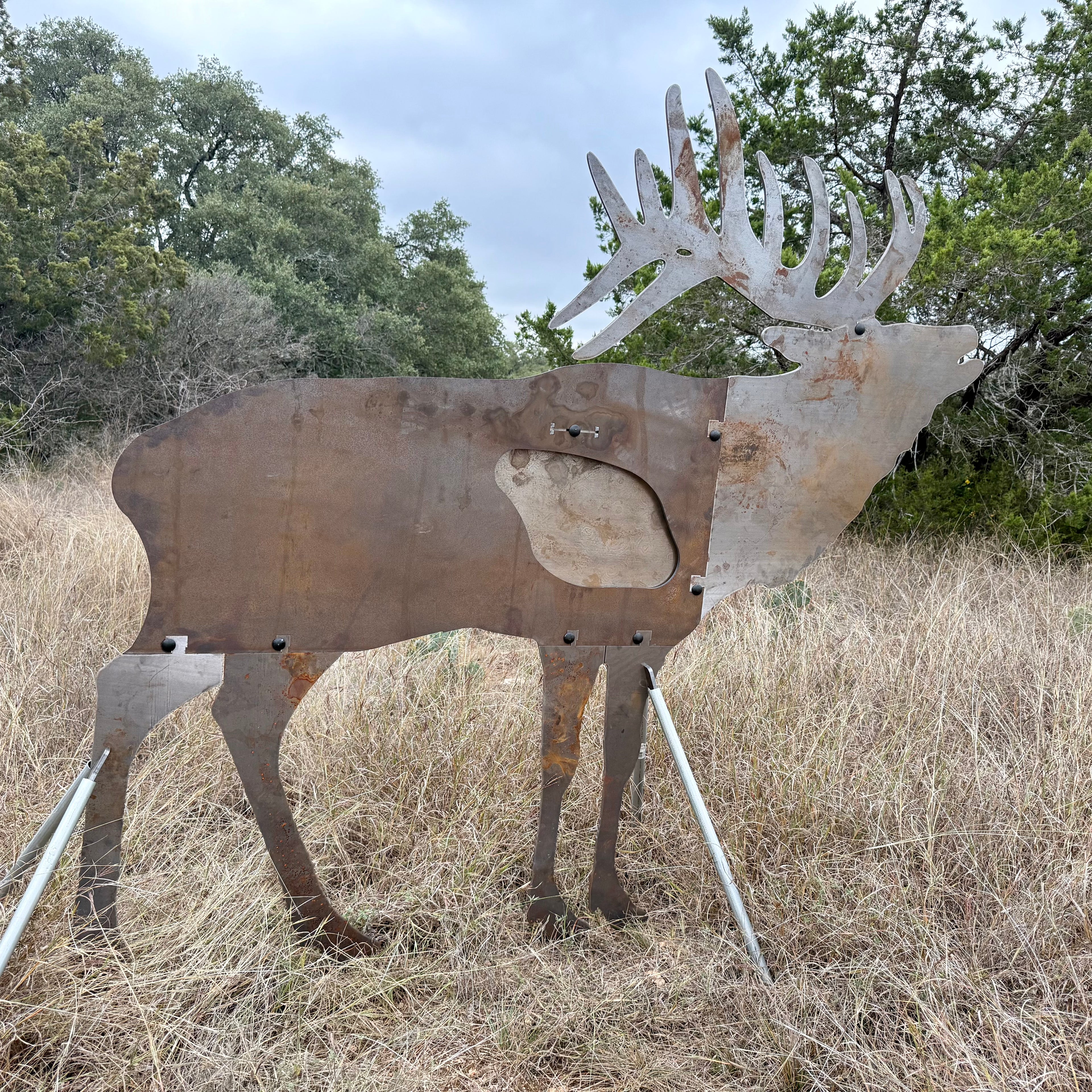 AR500 Steel Elk Bull target on a stand in a grassy outdoor area with trees in the background