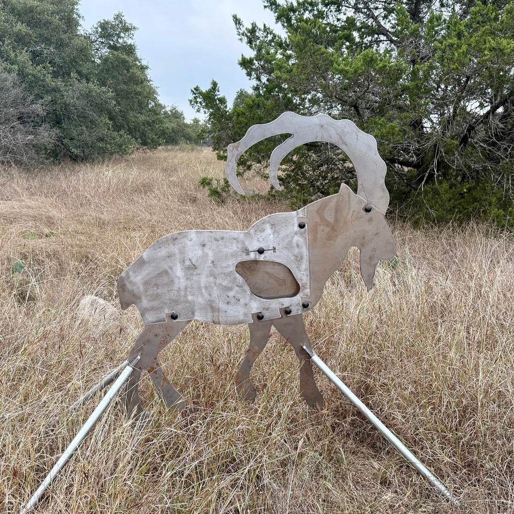 AR500 Steel Ibex Ram target on a stand in a grassy field with trees in the background