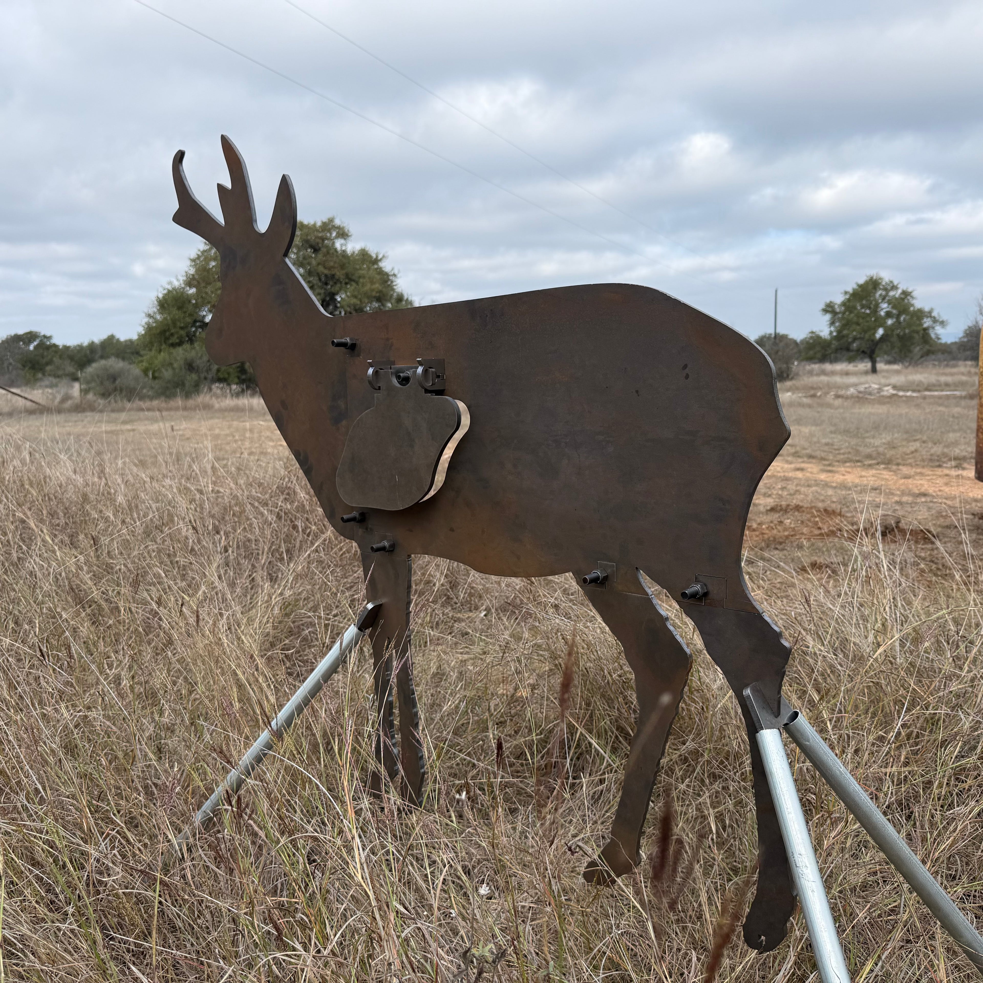AR500 Steel Pronghorn Antelope target on a stand in a grassy outdoor area with trees in the background